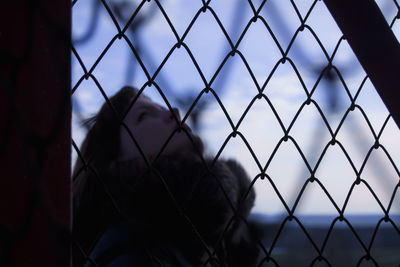 Woman seen through chainlink fence