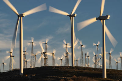 Windmills on field against sky