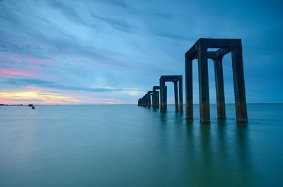 Pier over sea against sky at sunset