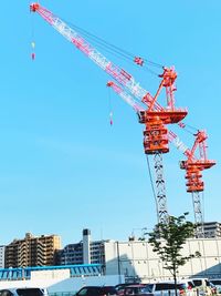 Low angle view of cranes at construction site against sky