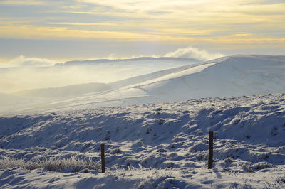 Scenic view of snow covered land against sky during sunset