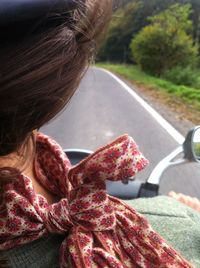 Rear view of woman riding motorcycle on road