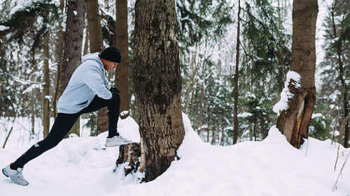 Woman standing by tree trunk during winter