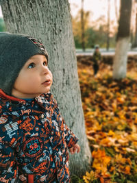 Portrait of girl standing against tree trunk