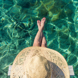 Directly above shot of woman wearing hat sitting by sea