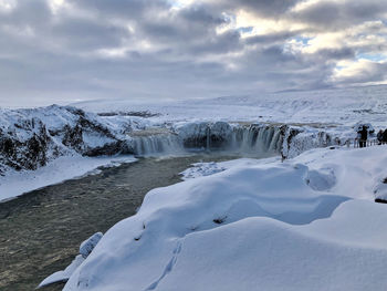 Scenic view of snowcapped mountains against sky with a waterfall