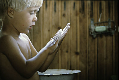 Shirtless boy washing hands in sauna