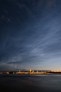 Buildings at waterfront against cloudy sky