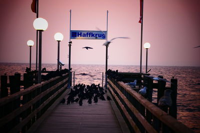 Street light by sea against clear sky during sunset