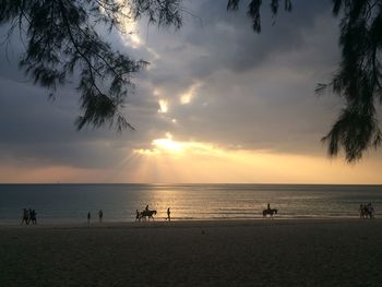 Silhouette people at beach against sky during sunset