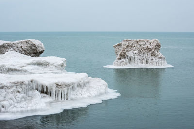 Scenic view of rocks in sea against clear sky