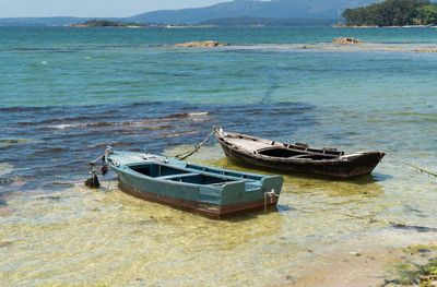 Boat moored on sea shore against sky