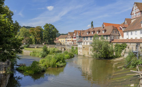 Scenic view of river by buildings against sky