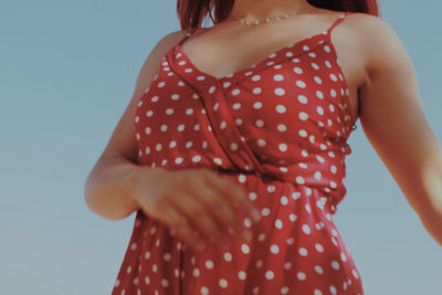 Midsection of woman with red hair standing against clear sky