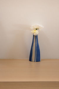 Close-up of flower vase on table against wall