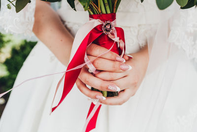 Midsection of bride holding flower bouquet