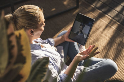 Woman talking with friend on video call through digital tablet on terrace