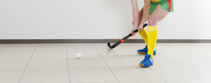 Low section of woman playing hockey on tiled floor