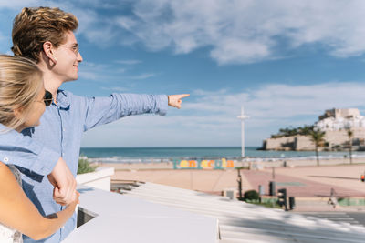 Woman standing by sea against sky