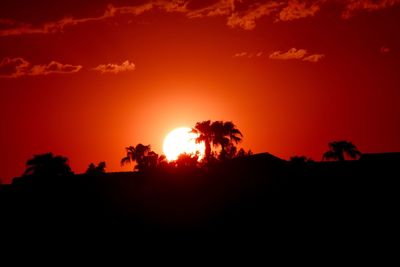Silhouette trees on landscape against romantic sky at sunset