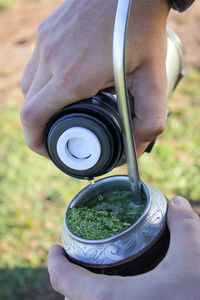 Cropped hands pouring water in container while preparing yerba mate