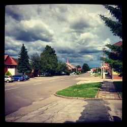 Road passing through city against cloudy sky