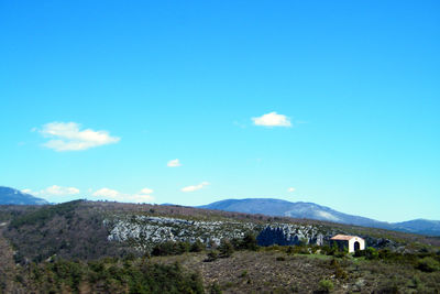 Scenic view of landscape and mountains against blue sky