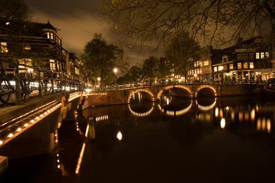 Illuminated bridge over canal in city at night