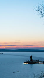 Silhouette man on beach against clear sky during sunset