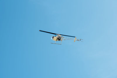 Low angle view of helicopter against clear blue sky