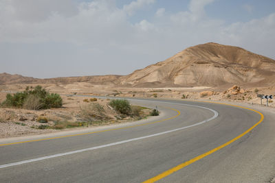 Road leading towards mountains against sky