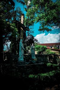 Statue against trees and building against sky