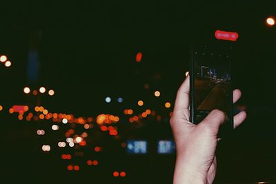 Close-up of hand on illuminated lighting equipment at night