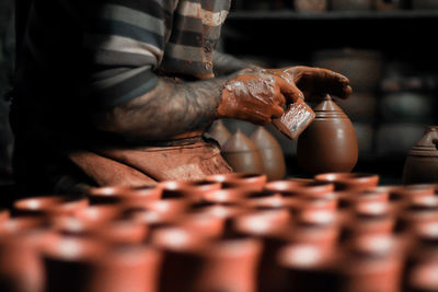 Midsection of man doing pottery in workshop