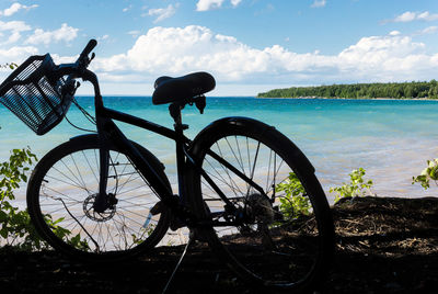 Bicycle by sea against sky