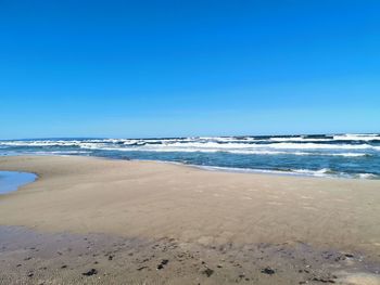 Scenic view of beach against clear blue sky