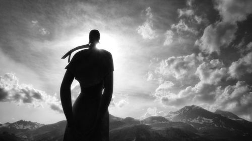 Rear view of silhouette man looking at mountains against sky