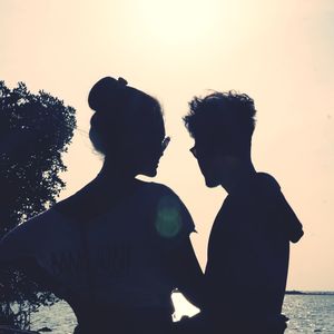 Silhouette couple standing against sky during sunset