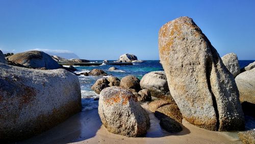 Rocks on beach against clear blue sky