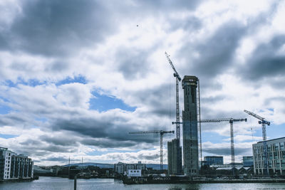 Cranes at construction site against sky