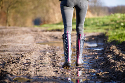 Low section of woman walking on dirt road