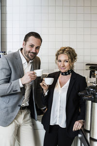 Portrait of smiling business people having coffee in kitchen