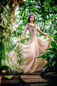 Portrait of beautiful bride wearing crown while standing on footpath amidst plants