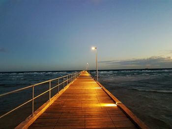 Pier over sea against clear sky during sunset