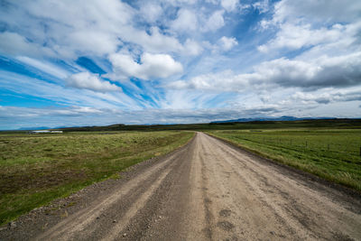 Road amidst field against sky