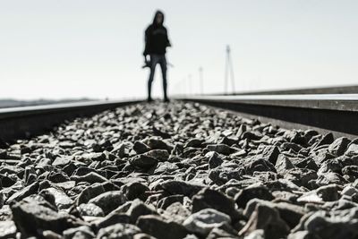 Close-up of person walking on railroad track against clear sky