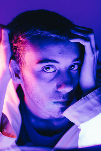 Close-up portrait of young man in illuminated room