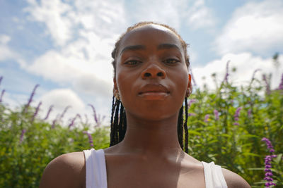 Portrait of young woman standing against sky