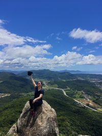 Man sitting on rock against mountains against sky