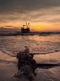 Silhouette boat in sea against sky during sunset